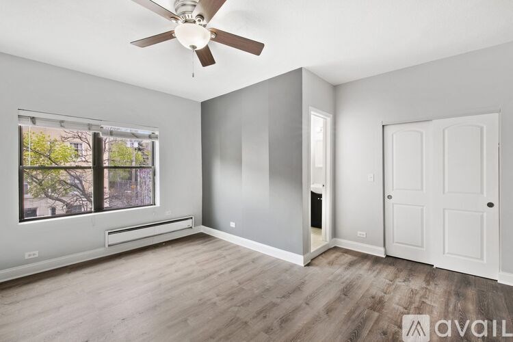 A room with a ceiling fan and a window with a view of trees.