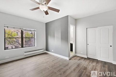 A room with a ceiling fan and a window with a view of trees.