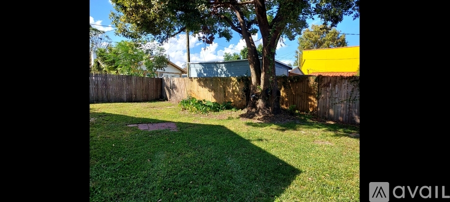 A backyard with a tree and a wooden fence.