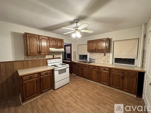 A kitchen with wooden cabinets and a white stove top oven.