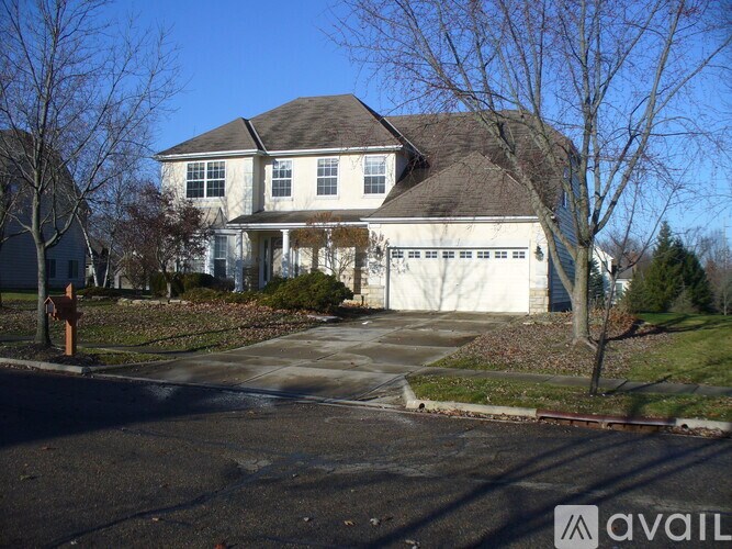 A large white house with a brown roof and a driveway in front.