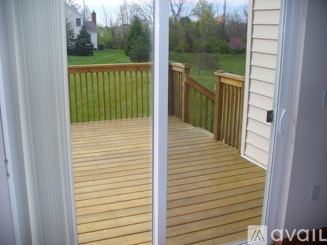 A wooden deck with a view of a green lawn and trees.