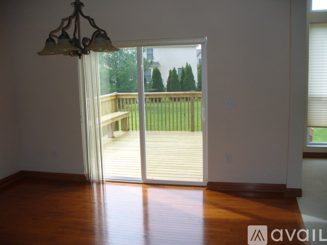 A room with a wooden floor and a chandelier with a sliding glass door leading to a deck.