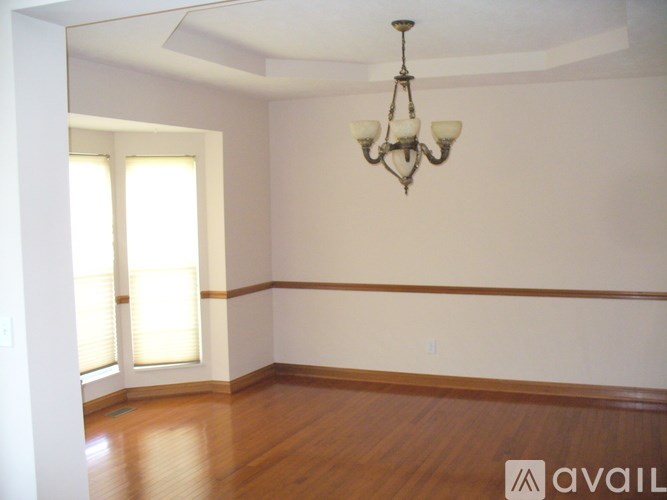 A room with a chandelier and a window with blinds.