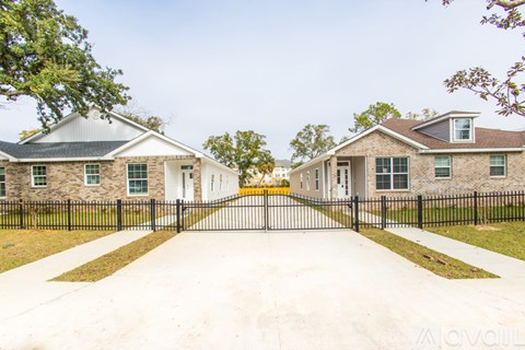 A row of houses with black fences and green trees in front.
