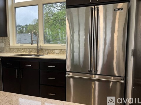 A kitchen with a stainless steel refrigerator and black cabinets.