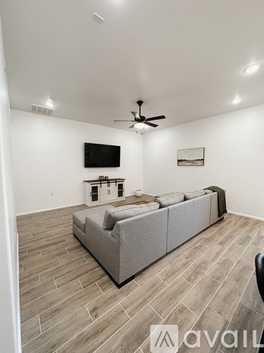 A living room with a grey couch and a television on the wall.