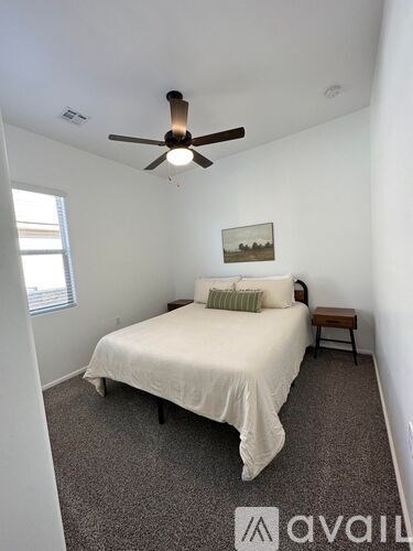 A bedroom with a bed, a ceiling fan, and a small table.