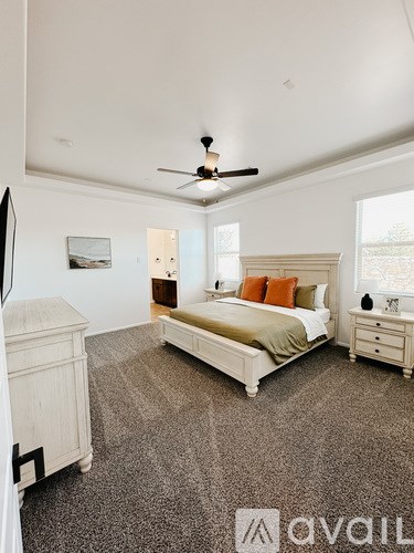 A bedroom with a large bed, a dresser, and a ceiling fan.
