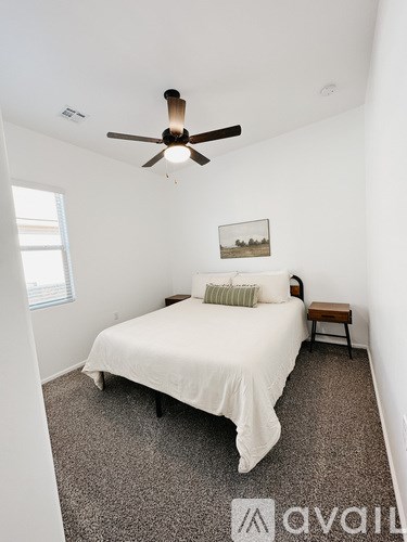 A bedroom with a bed, a bench, and a ceiling fan.