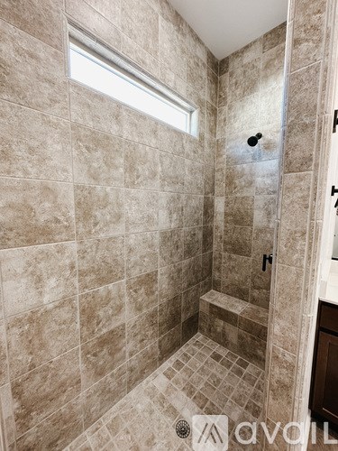 A bathroom with a tiled shower and a window.