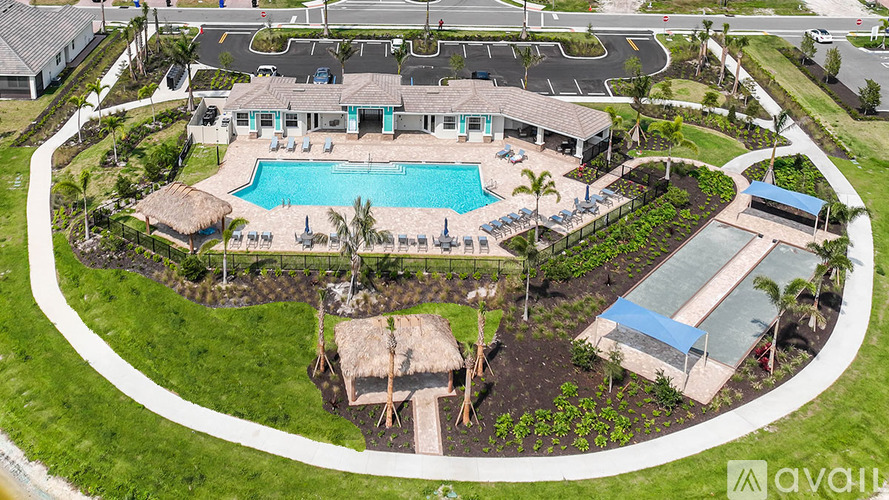 A pool surrounded by a grassy area and a building in the background.