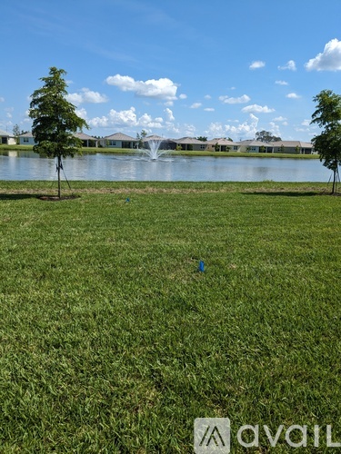 A grassy field with a lake and trees in the distance.
