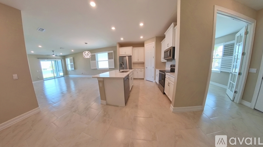 A spacious kitchen with white cabinets and appliances, a dining table, and a large window.
