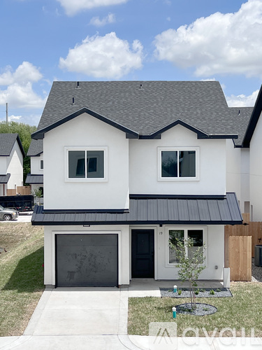A white house with a black roof and a black garage door.