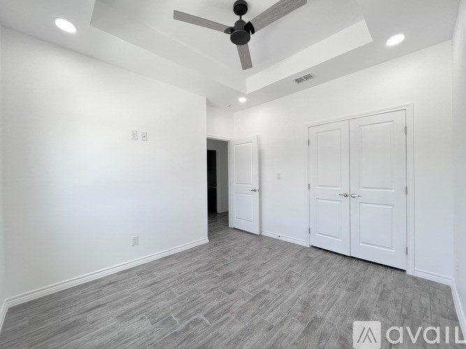 A spacious room with a ceiling fan and two doors.