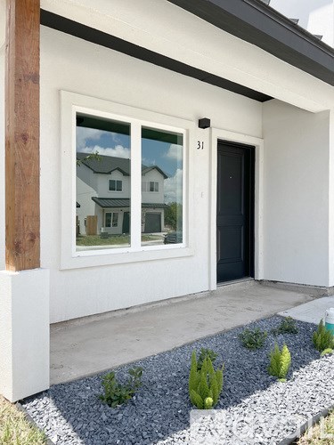 A white house with a black door and a window showing a reflection of a house.
