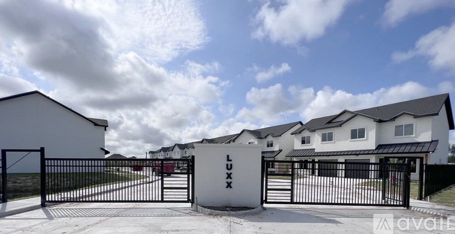 A gated entrance to a residential area with houses in the background.