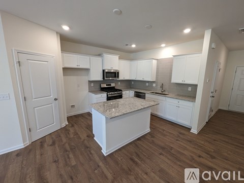 A kitchen with white cabinets and a granite countertop is available for rent.