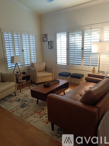 A living room with a brown leather couch and a rug.
