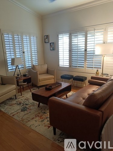 A living room with a brown leather couch and a rug.