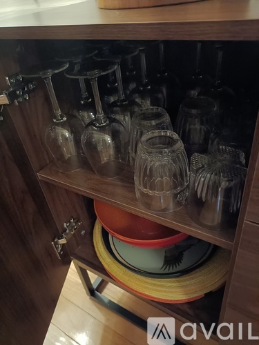 A kitchen cabinet with glasses and plates stacked inside.