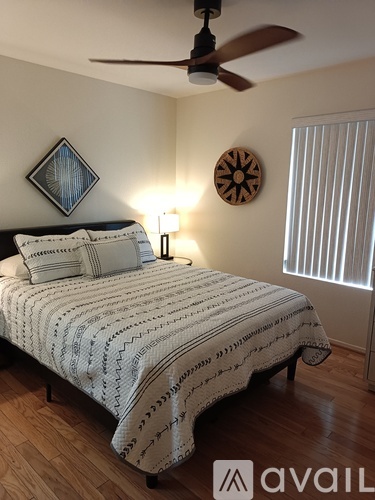 A bedroom with a bed, a ceiling fan, and a wall clock.