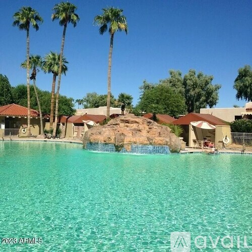 A pool surrounded by palm trees and a rocky outcrop.