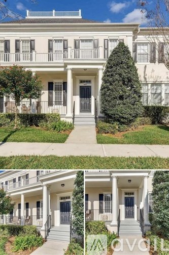 A white two-story house with a front porch and a tree in front.