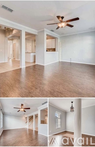 A living room with a ceiling fan and a kitchen area in the background.