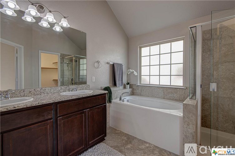 A bathroom with a large tub and a double sink vanity.