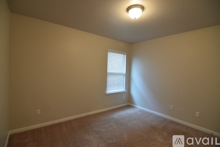 A room with a carpeted floor, a door, and a window with blinds.