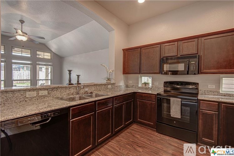 A kitchen with dark wood cabinets and a black oven.