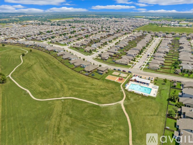 A bird's eye view of a suburban neighborhood with a swimming pool and a winding road.