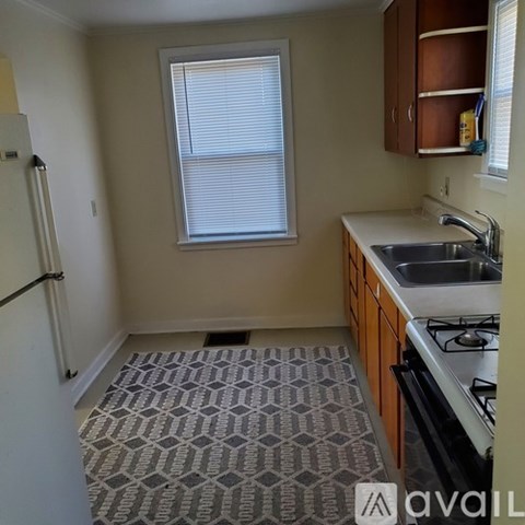 A kitchen with a sink, stove, and a window with blinds.