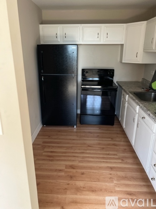 A kitchen with black appliances and white cabinets.