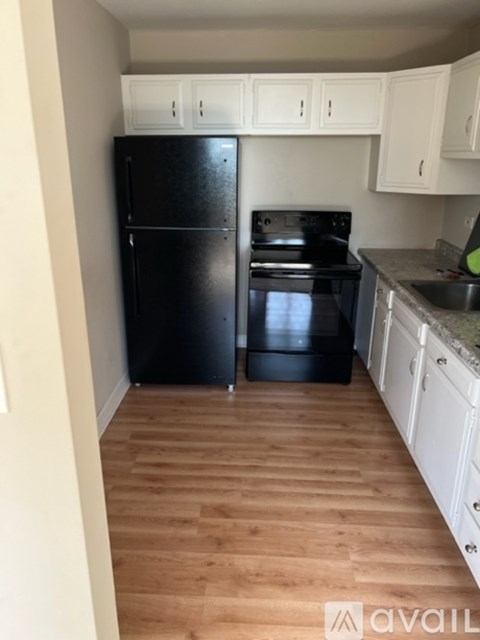A kitchen with black appliances and white cabinets.