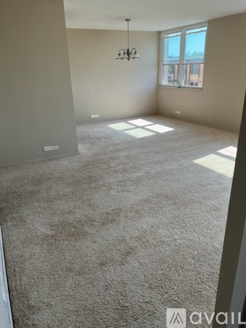 A room with a carpeted floor and a chandelier hanging from the ceiling.