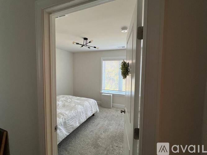 A bedroom with a bed, window, and carpet.