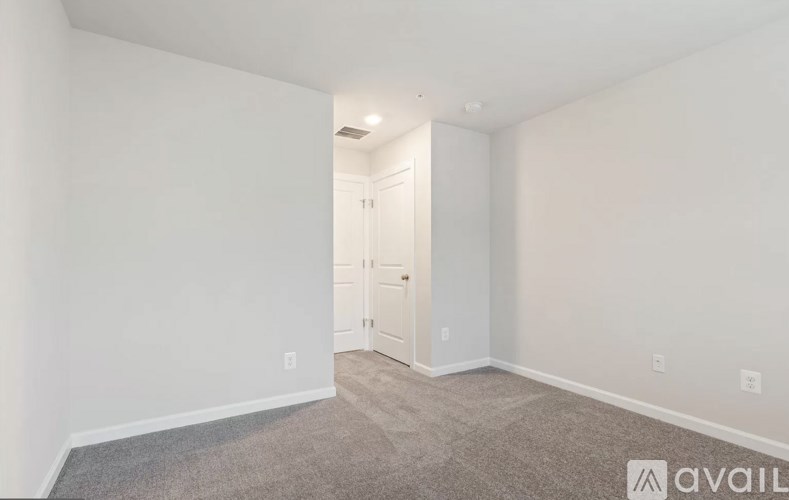 A room with a carpeted floor and a door in the background.