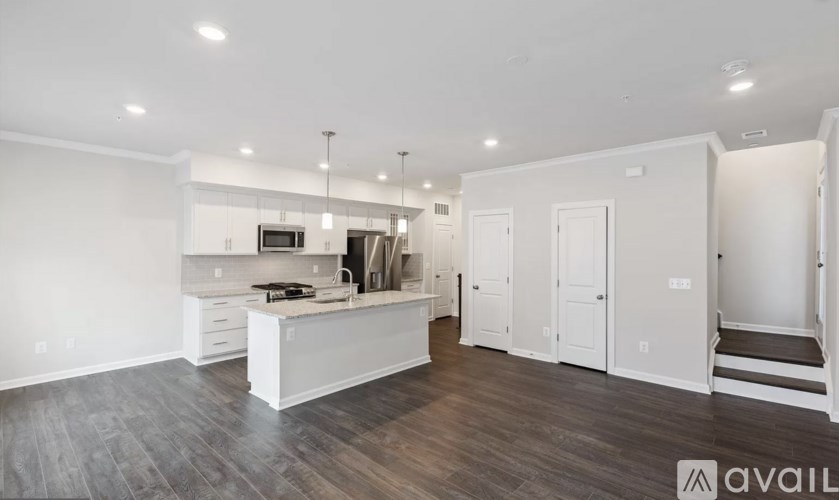 A spacious kitchen with white cabinets and a wooden floor.
