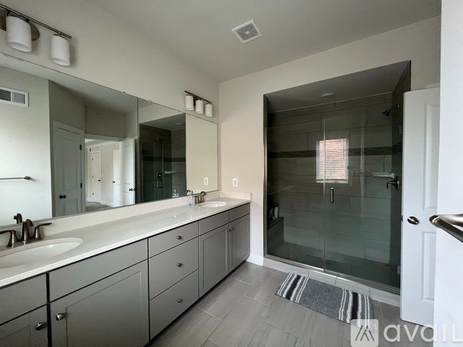 A bathroom with a sink, mirror, and shower.