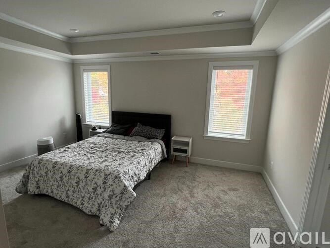 A bedroom with a bed, nightstand, and window.