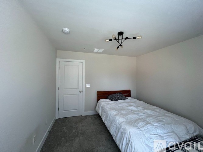 A bedroom with a bed, a door, and a ceiling fan.