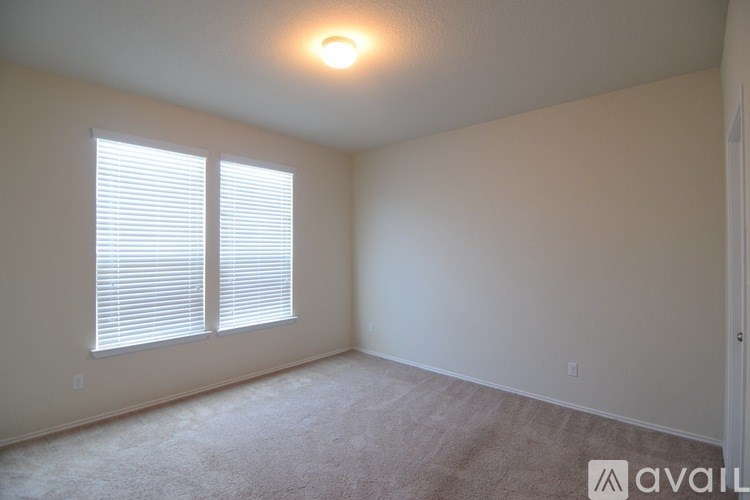 A room with a carpeted floor and a window with blinds.