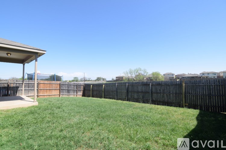 A backyard with a wooden fence and a covered patio area.
