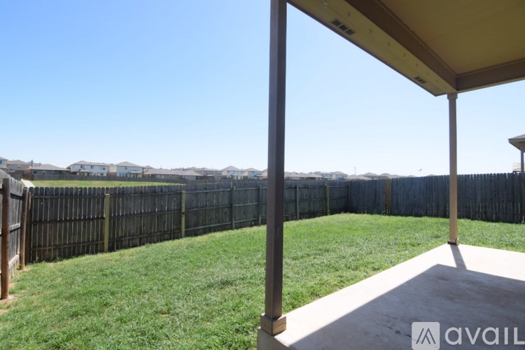A patio with a view of a fence and houses in the distance.