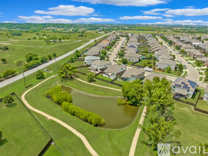 A bird's eye view of a residential area with houses, a pond, and a road.