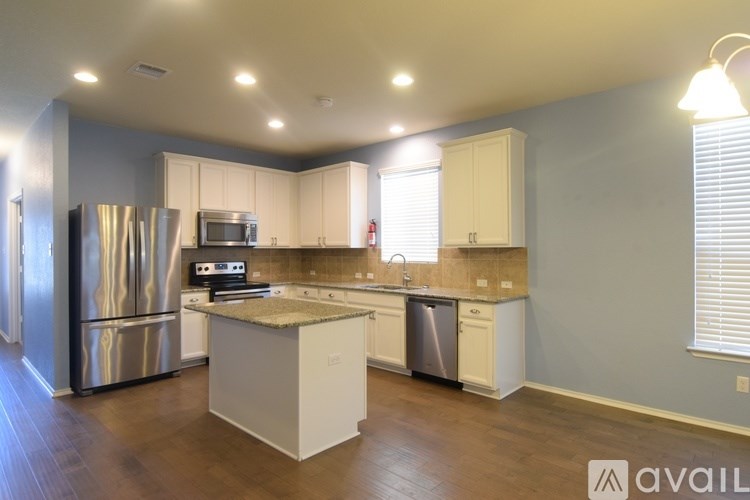 A kitchen with a refrigerator, microwave, oven, and sink.