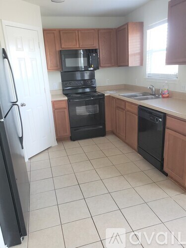 A kitchen with black appliances and brown cabinets.
